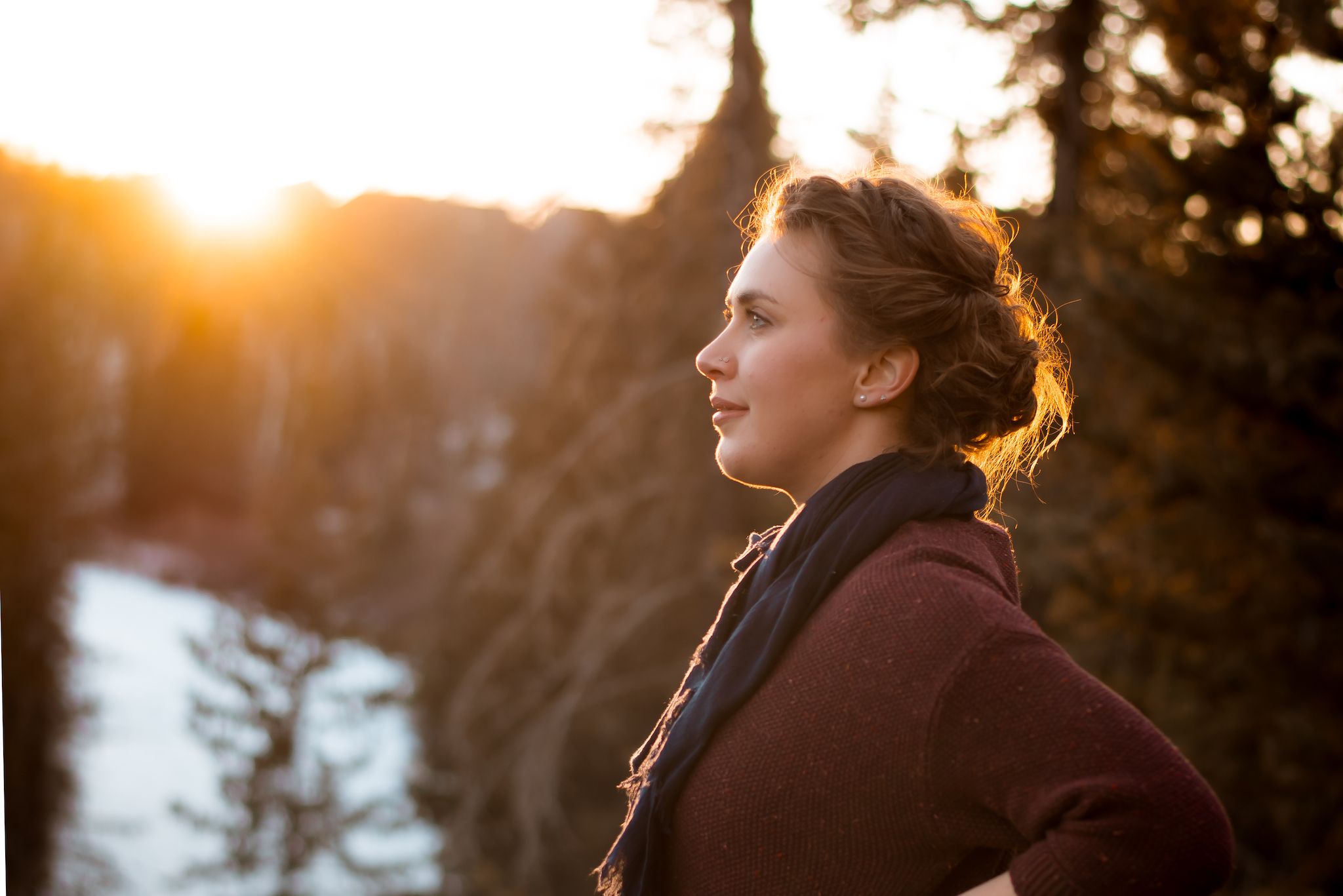Golden sunlight illuminates profile against winter mountain landscape.