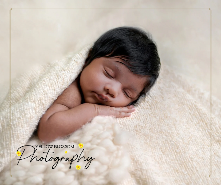 A peaceful sleeping newborn baby wrapped in soft white blanket during professional photography session. Haverhill, Suffolk