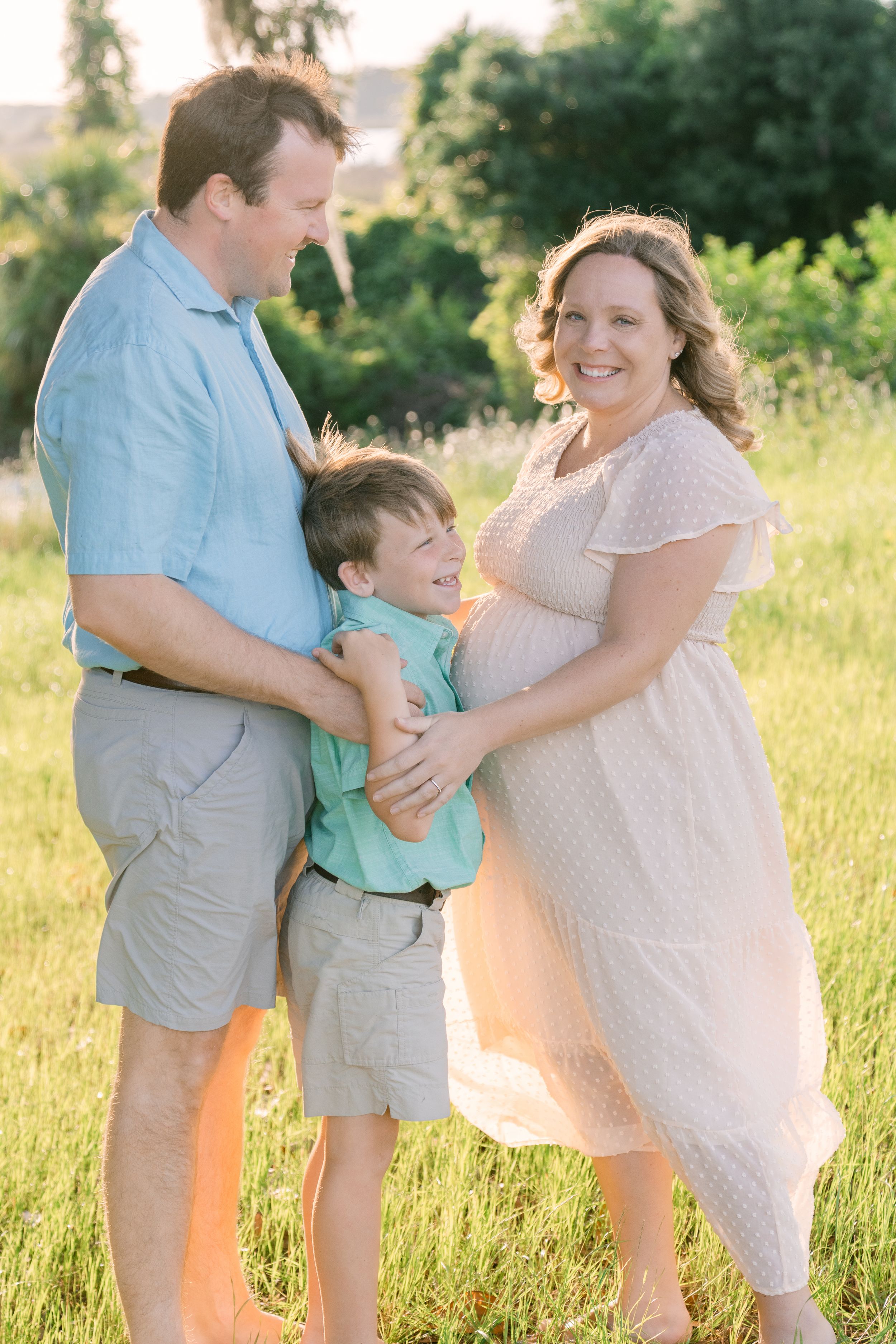 maternity portraits family photography session in Coastal Georgia, Darien, GA at sunset near the marsh, family of three smiling with hugs