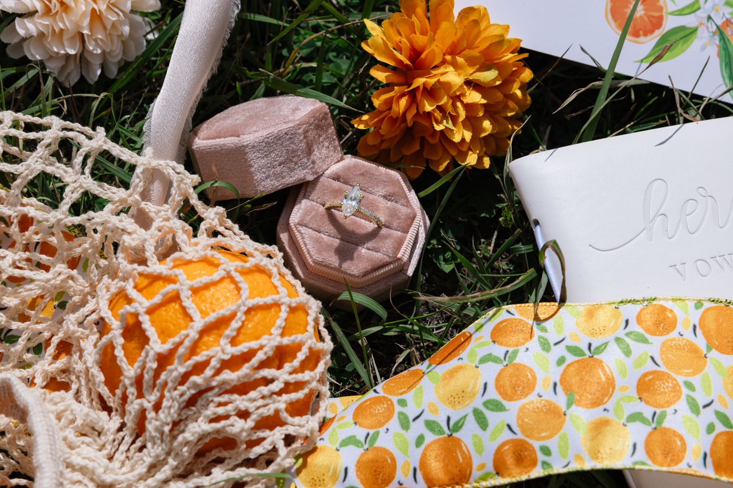 Flat lay of orange autumn decor items with wooden stamps, a mesh produce bag, and fabric with citrus pattern.