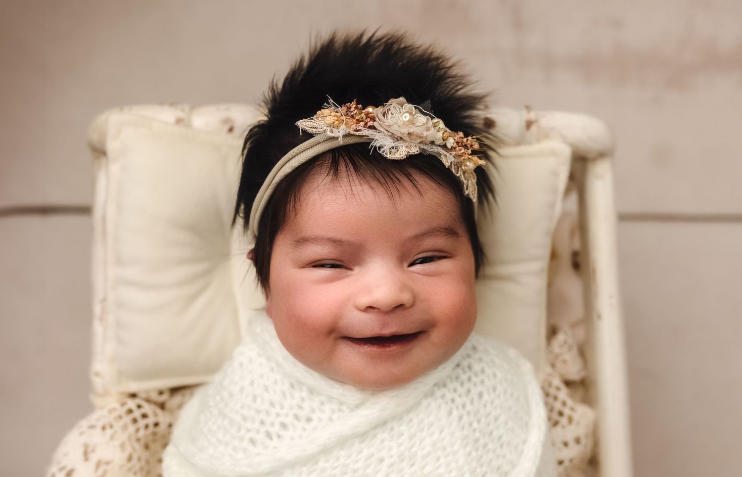 Harrisonburg photographer, newborn baby with beautiful dark hair and a headband smiling in a spindle crib in Charlottesville, Virginia.