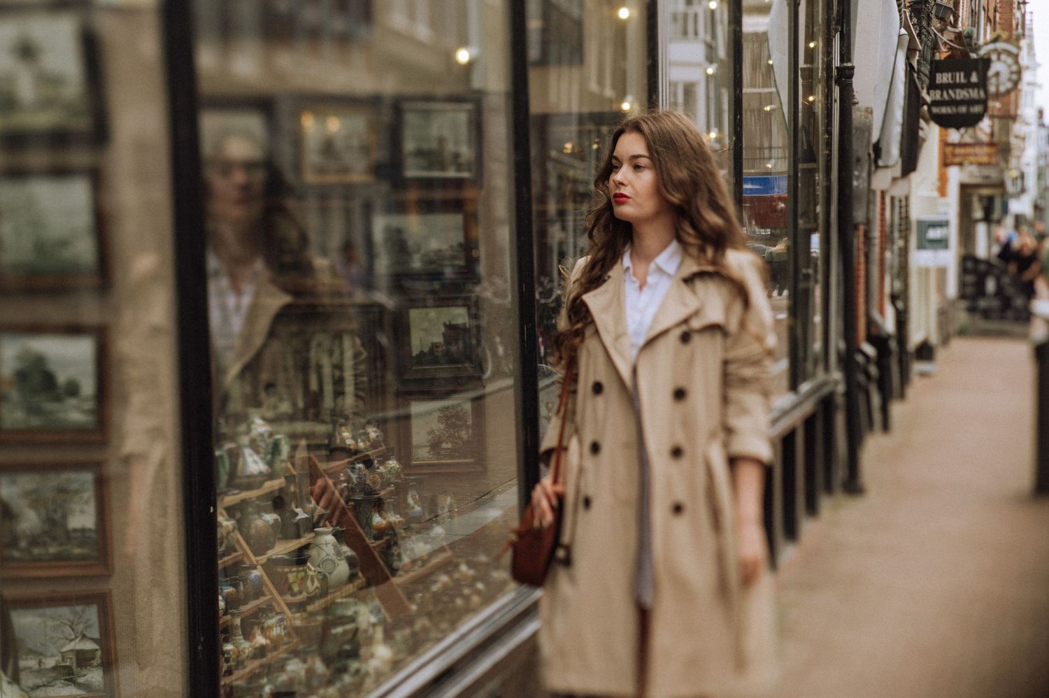 A woman stands by the window of a vintage store in Amsterdam, looking at her reflection.