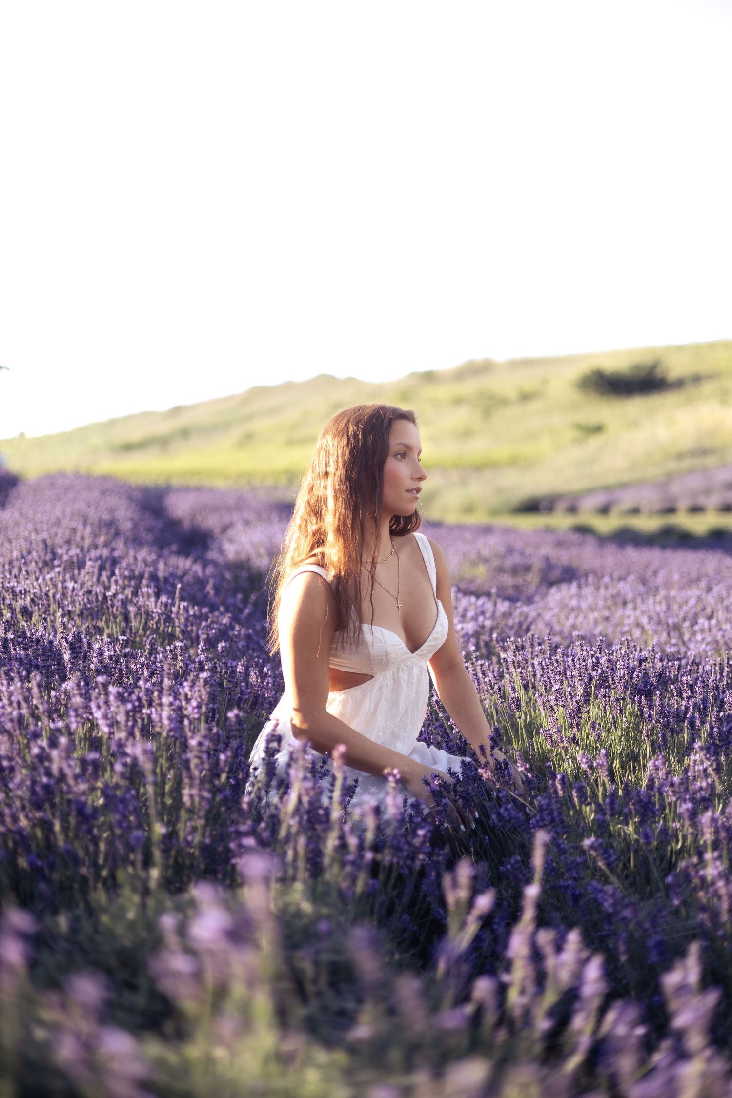 Ethereal figure in a flowing white dress stands peacefully among vibrant purple lavender fields at golden hour.