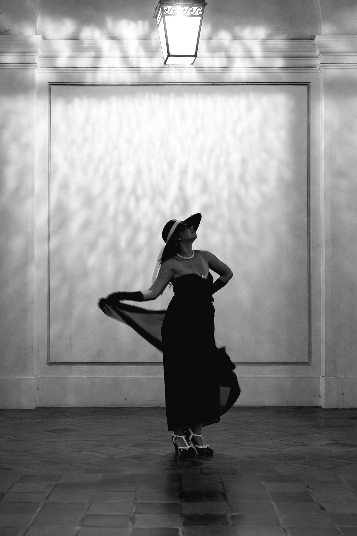 Silhouette of a dancer performing against a white wall with dramatic lighting.