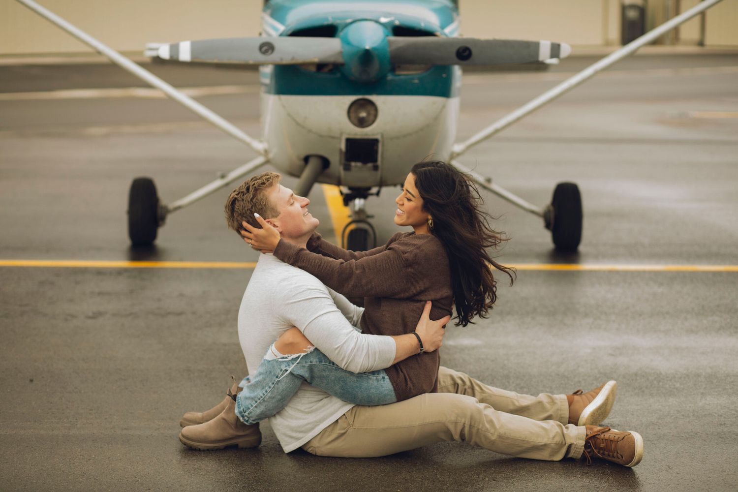 Couple sitting in front of a prop plane.