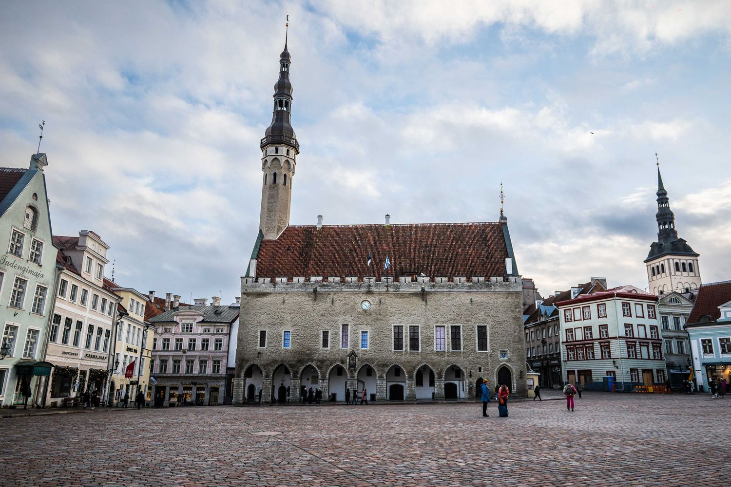 Historic town hall building with tall spire dominates medieval town square in European city center.