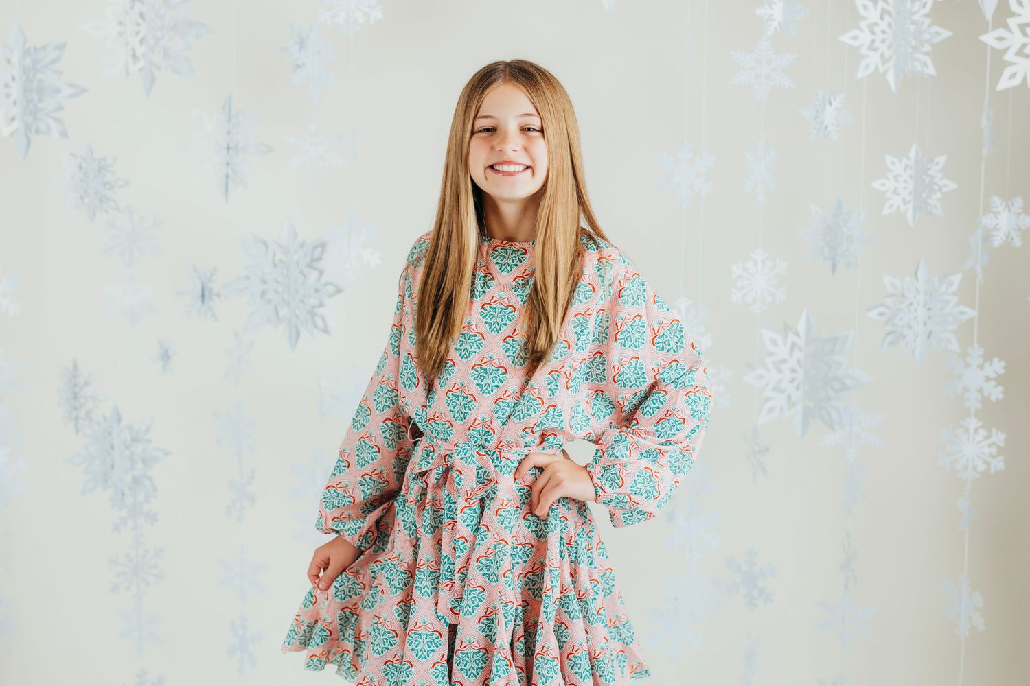 Portrait against white background featuring a floral dress and long blonde hair.