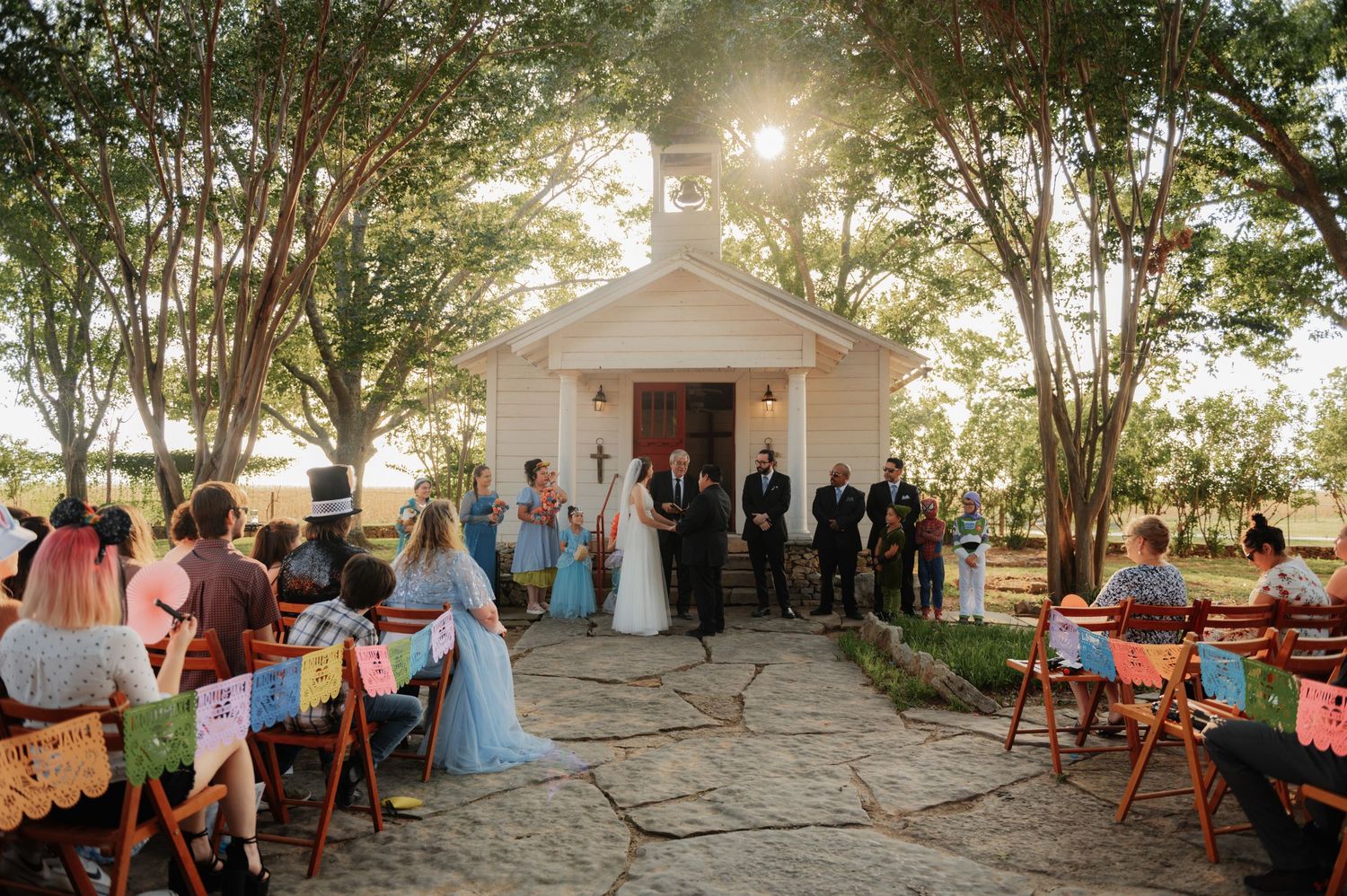 Bride and groom exchange vows at rustic indoor wedding ceremony with white chairs and floral arrangements.