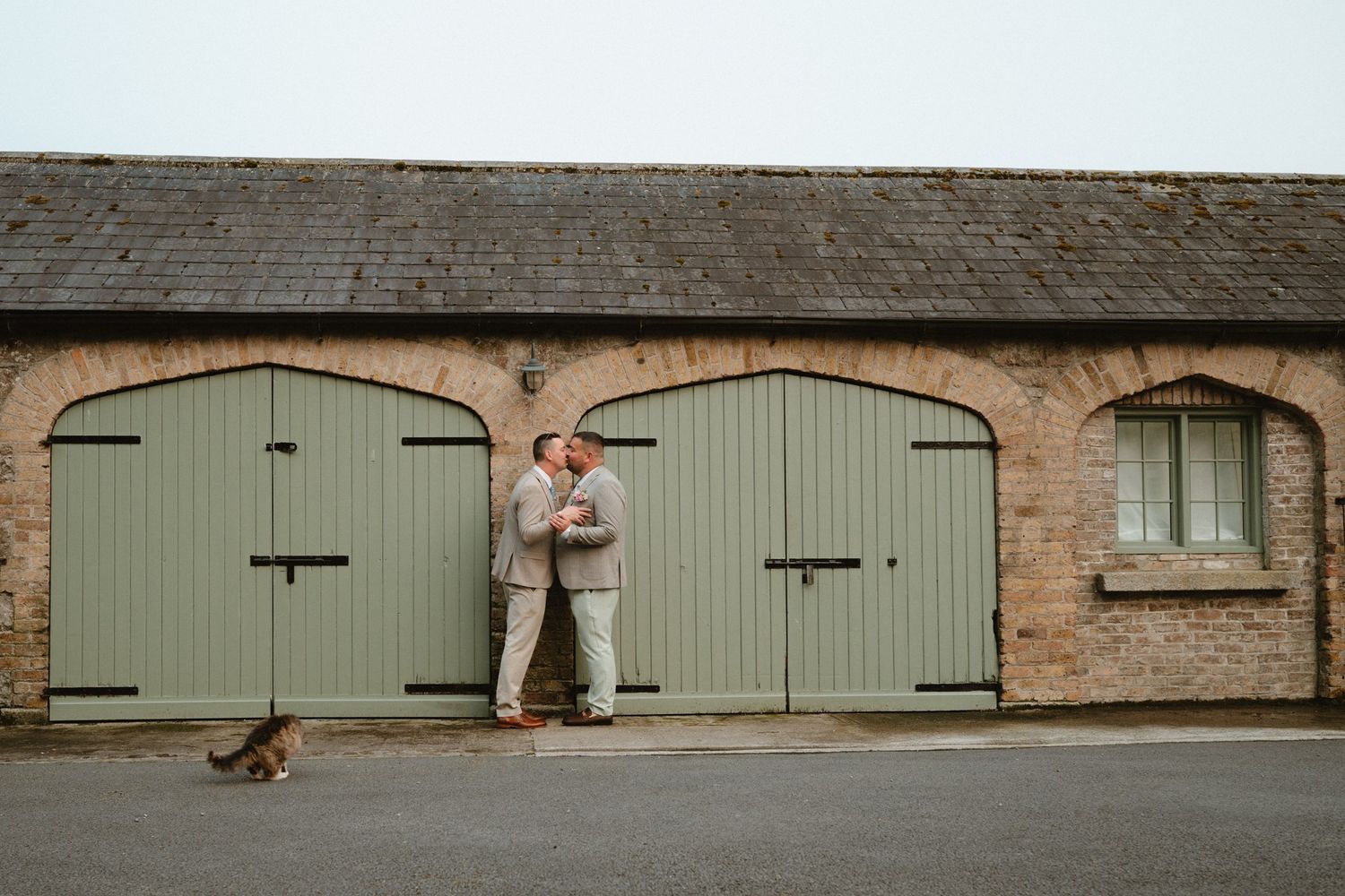 Adrian and Tom embracing beside the green doors at Martinstown House.
