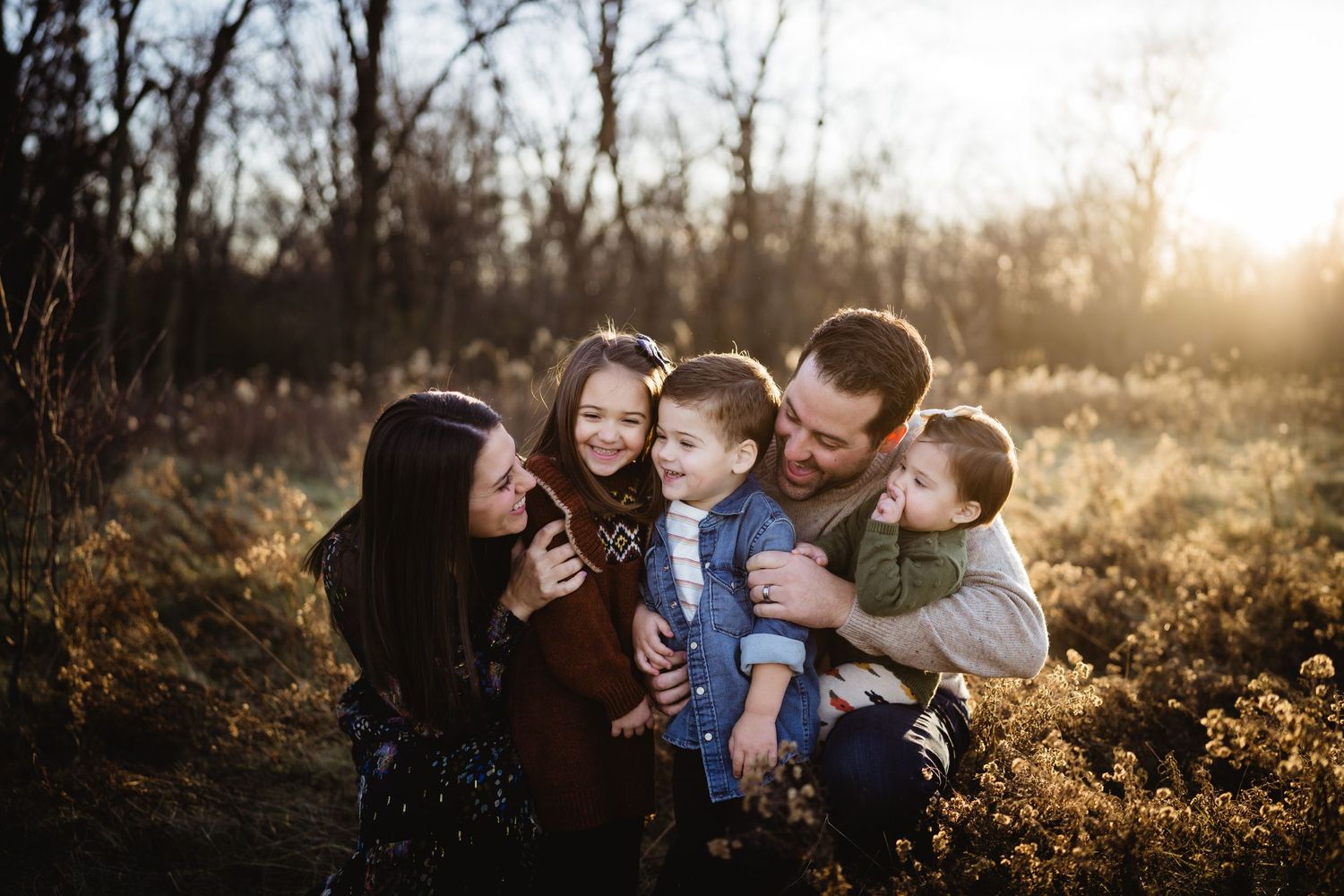 A loving family moment captured outdoors during golden hour among autumn foliage.