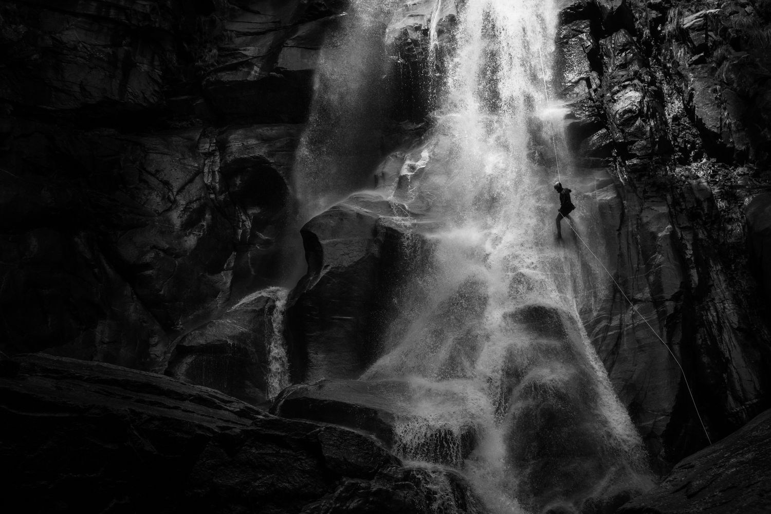 Black and white dramatic abseiling rapelling canyoning waterfall in Ticino Switzerland by the Adventure Photographers