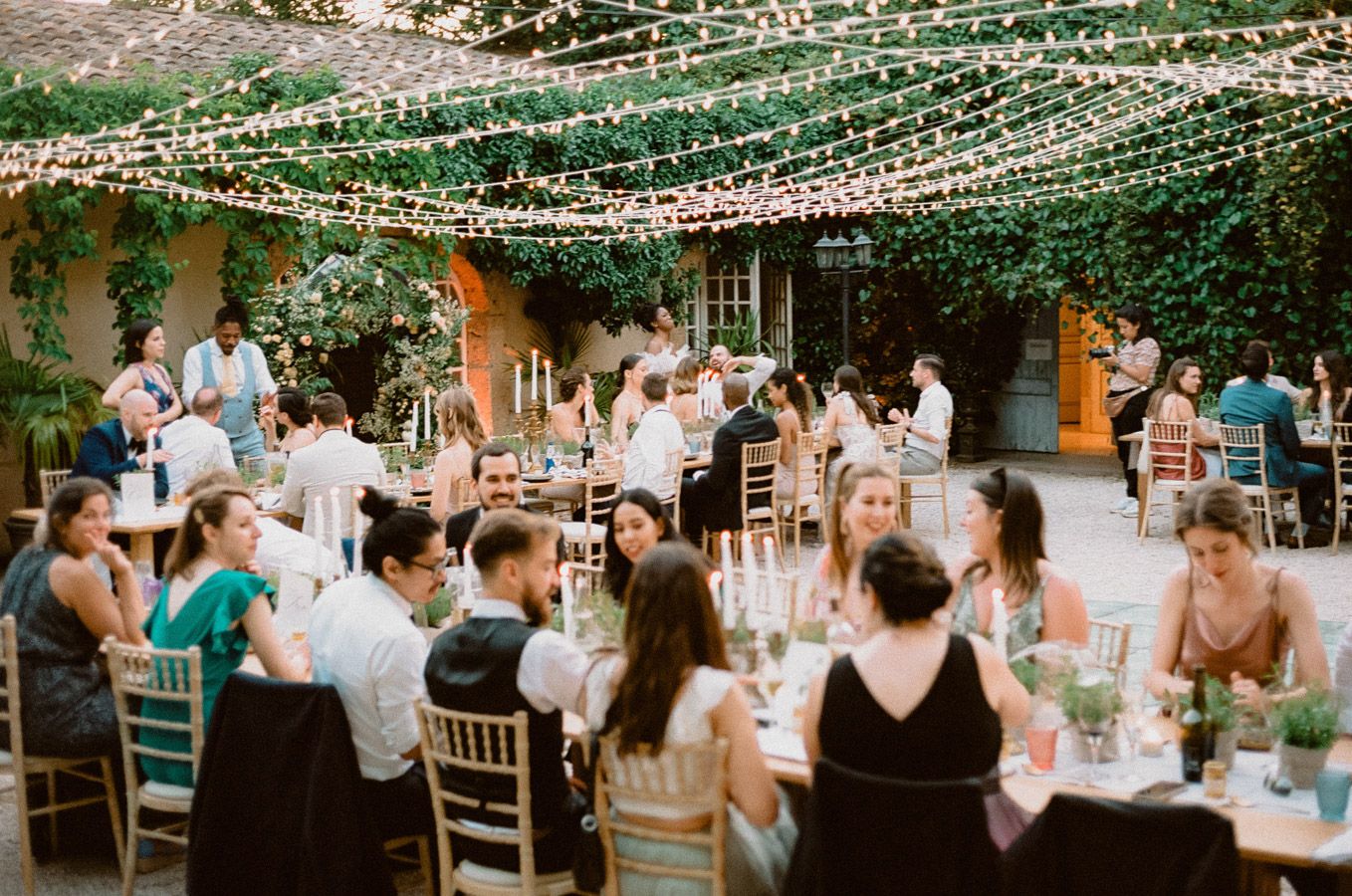 Elegant outdoor wedding reception with string lights and dining tables set beneath a canopy of twinkling lights.