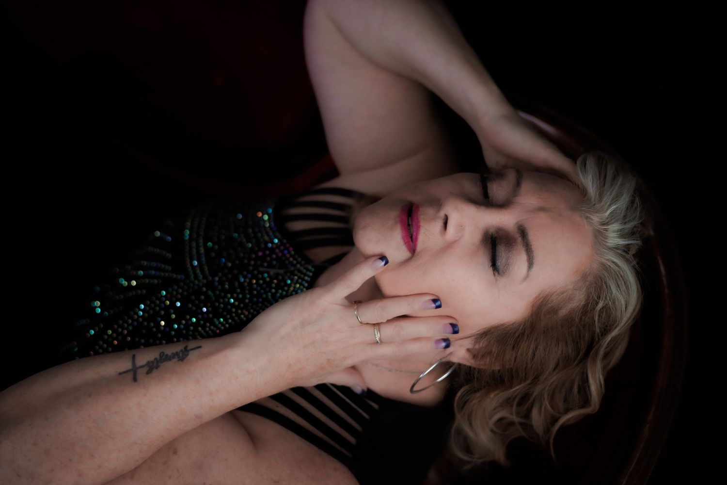 Dramatic portrait of woman in sparkling dress against dark background.