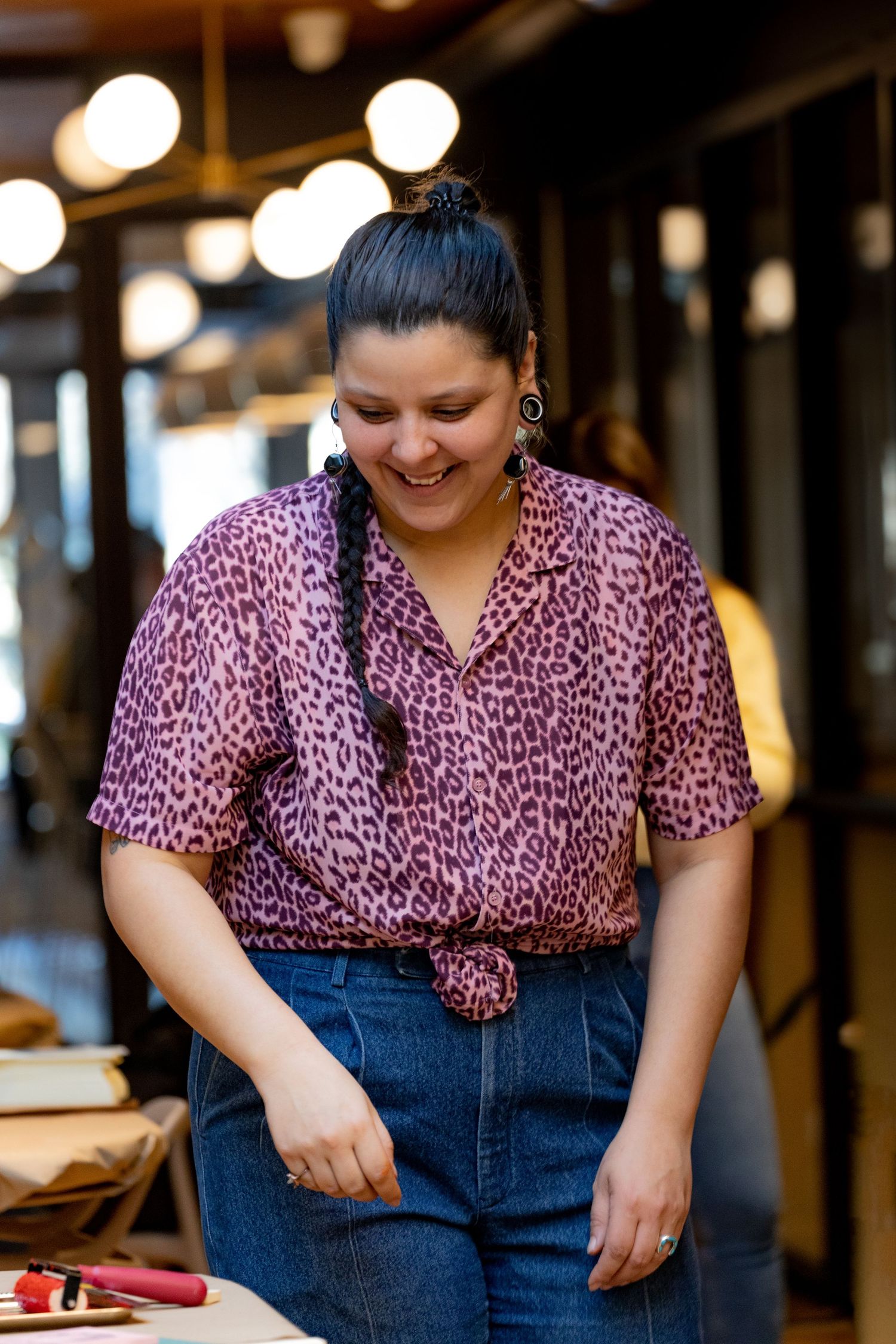 A person wearing a pink leopard print shirt smiles while leading a workshop.