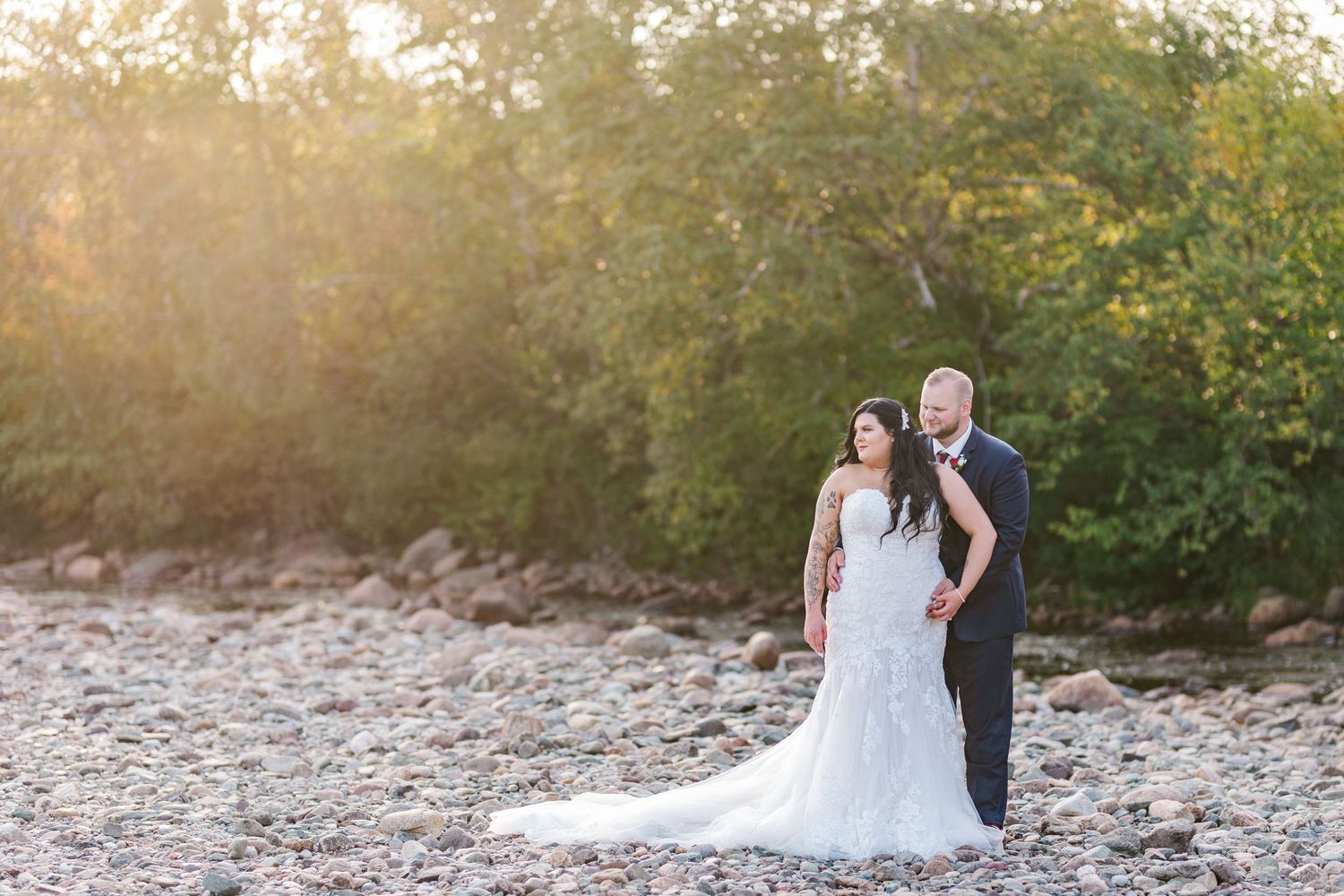 Golden sunlit wedding photos captured on a rocky beach during sunset with warm autumn colors.
