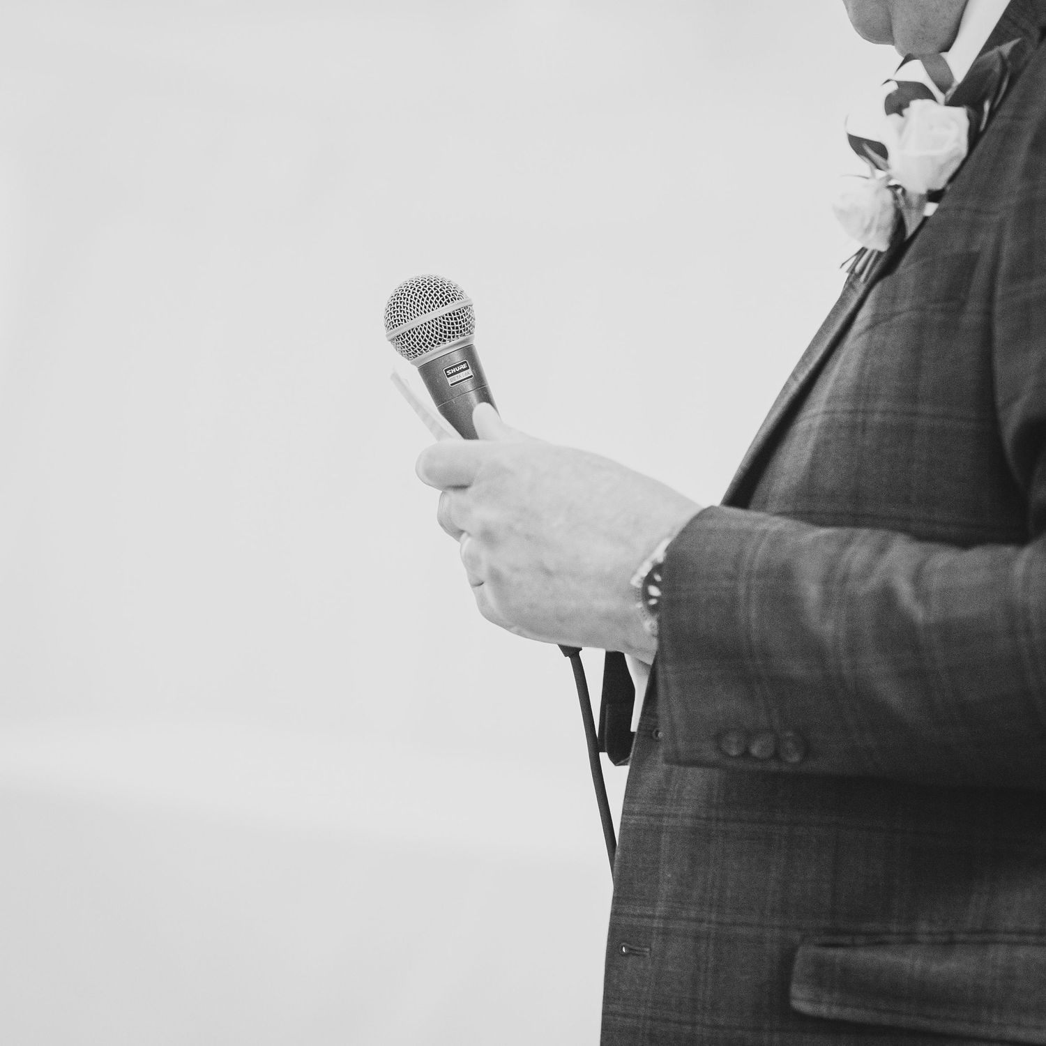 Close-up black and white shot of someone holding a microphone.