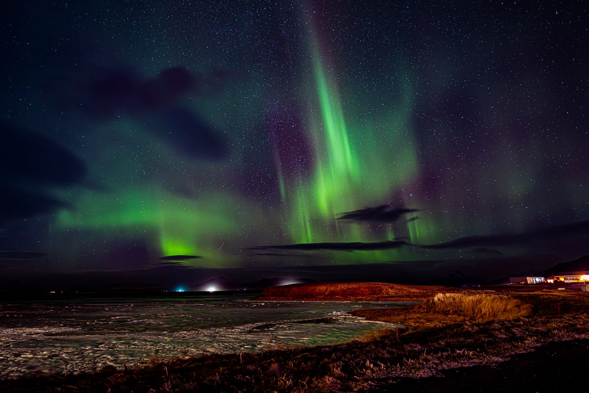 Vibrant green aurora borealis dancing across the night sky over a snowy landscape.
