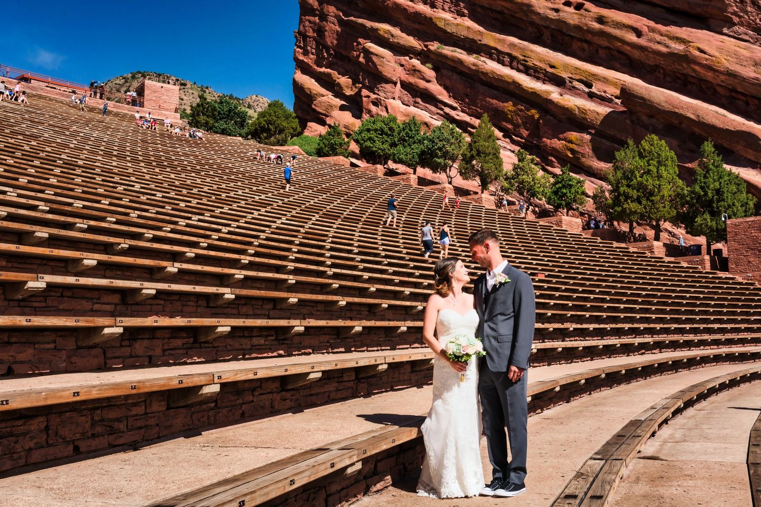 Wedding couple standing in the iconic Red Rocks Amphitheatre with rows of empty seats behind them.