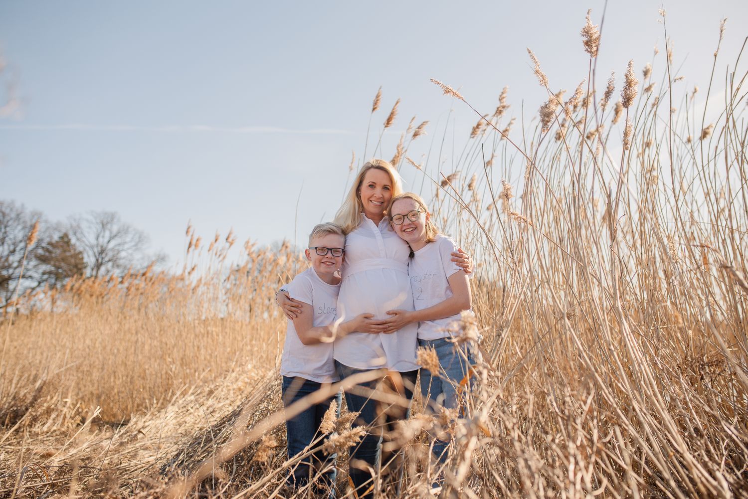 Family standing together among tall golden reeds in natural setting.