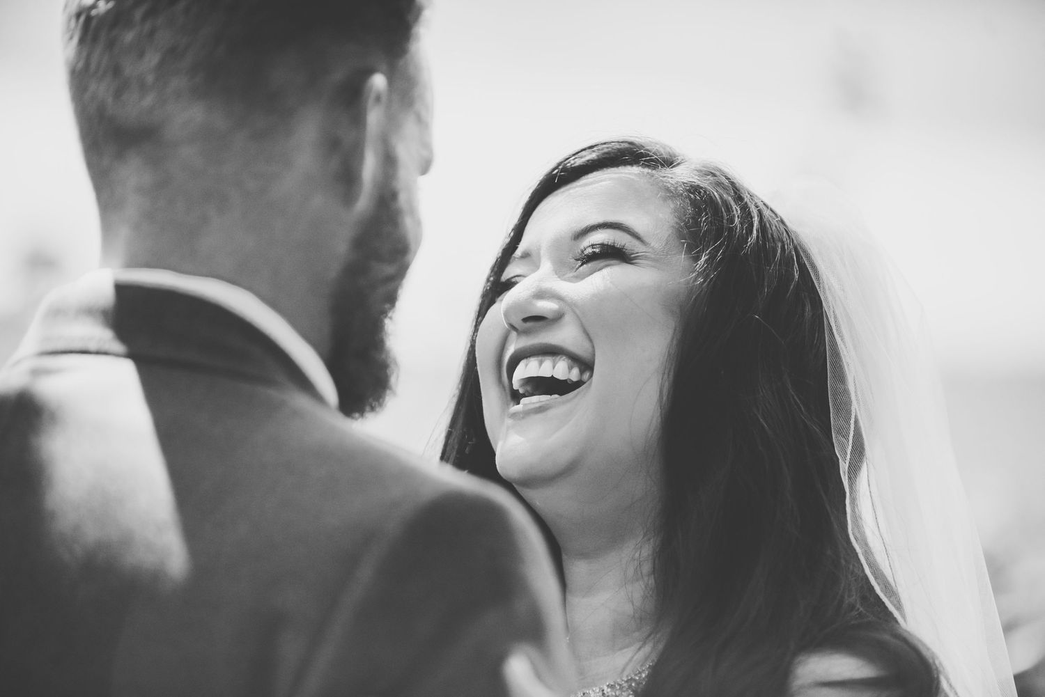 Black and white candid photo capturing joyful laughter during wedding celebration.