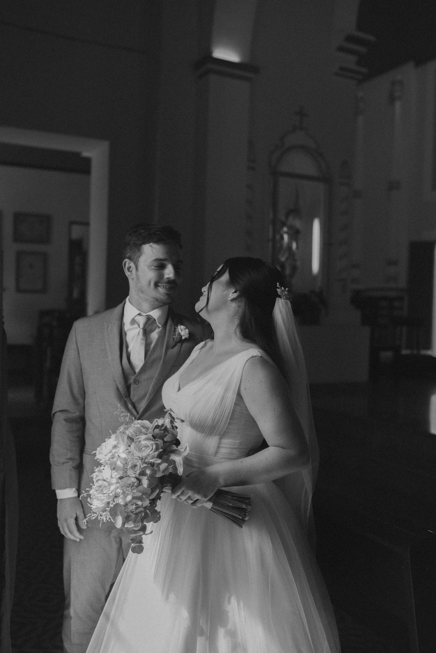 A couple shares a joyful moment in a church with elegant floral decorations.