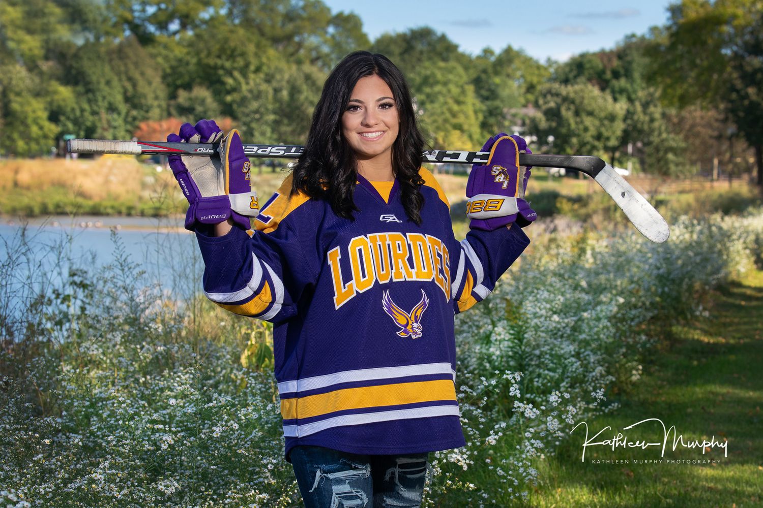 Senior girl with hockey stick posing for senior photos.