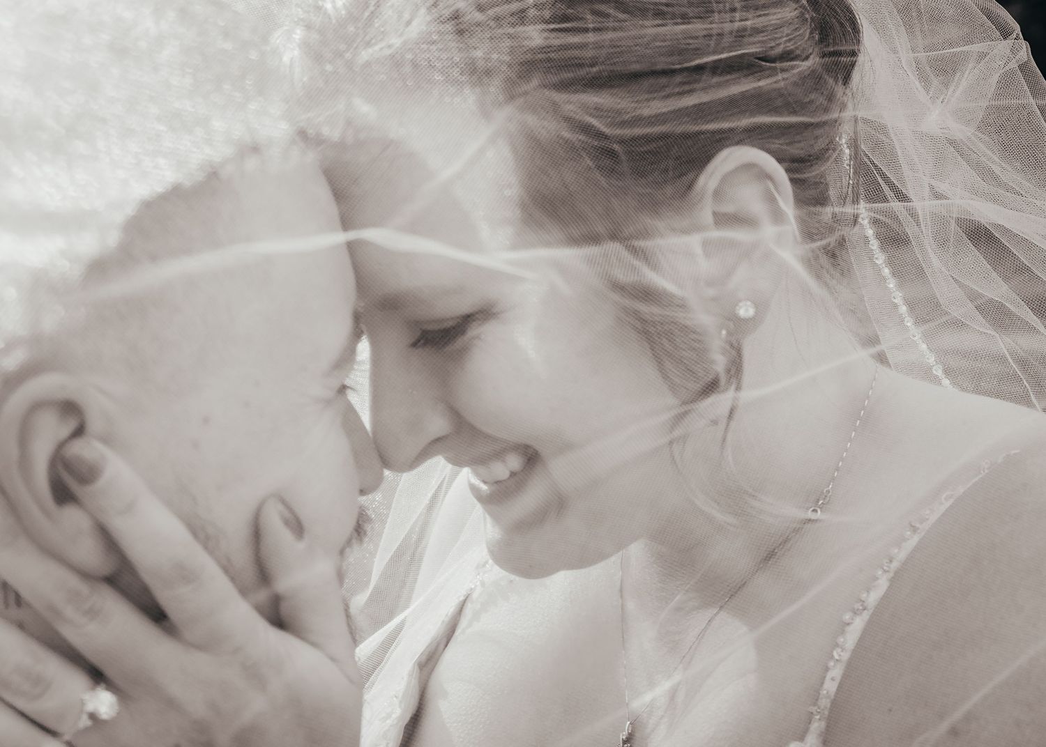 Bride and Groom almost kissing under veil during wedding portraits