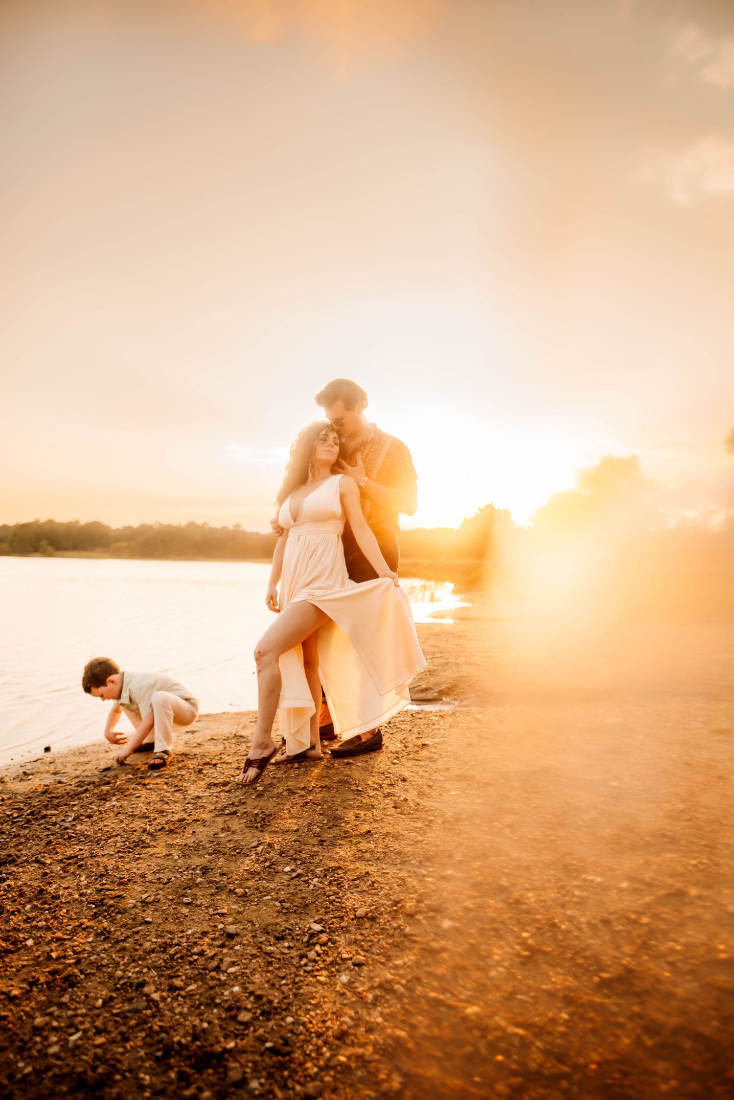 A family enjoys a sunset moment together on a rocky shoreline.