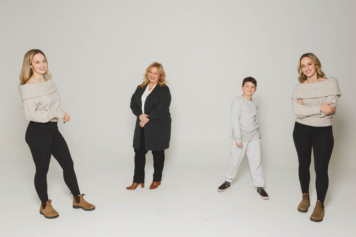 Studio portrait of family members in casual outfits against grey background.