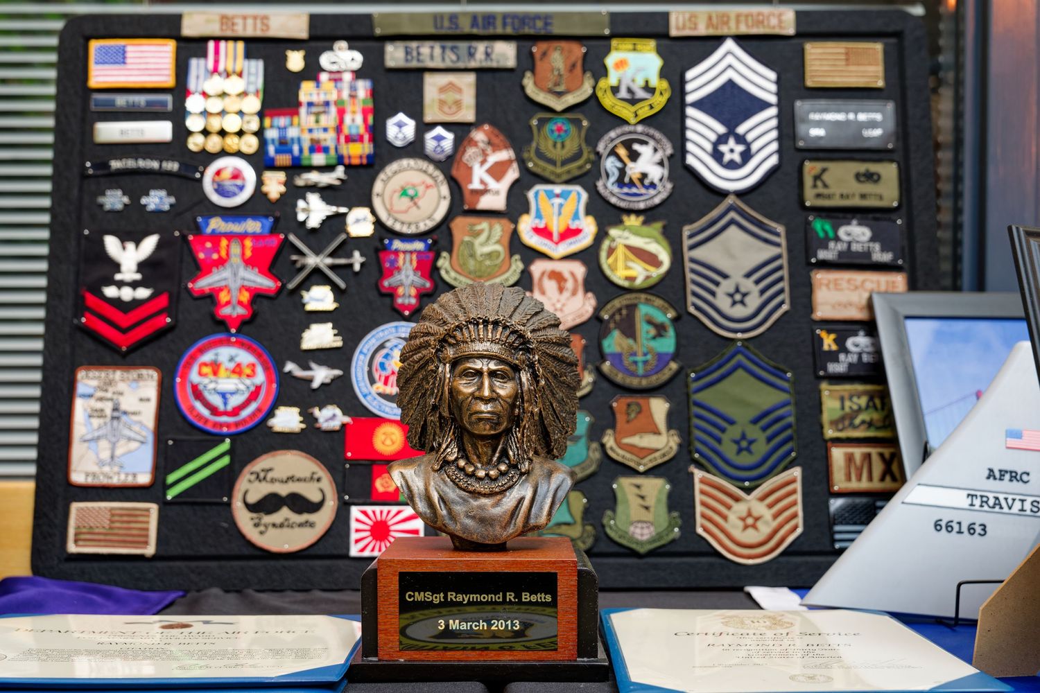 Military display board featuring Air Force patches, medals, rank insignia, and a Native American chief bust trophy.
