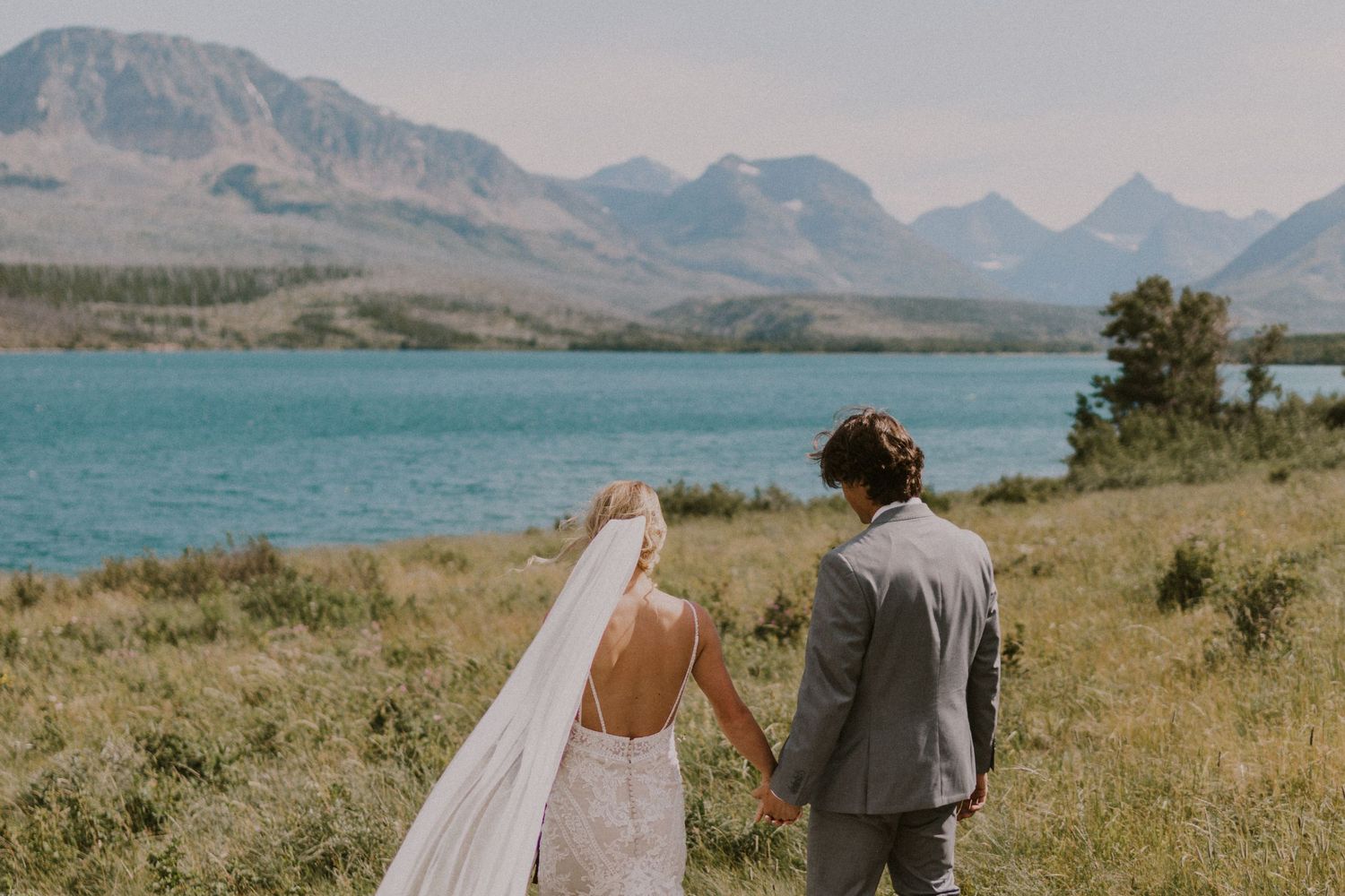 wedding couple on a trail in Glacier National Park overlooking a lake and beautiful mountains