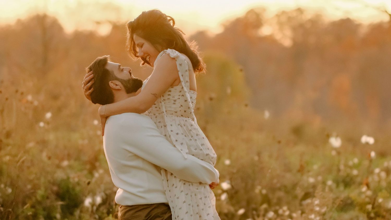A romantic scene of a couple embracing in a golden sunlit meadow at sunset.