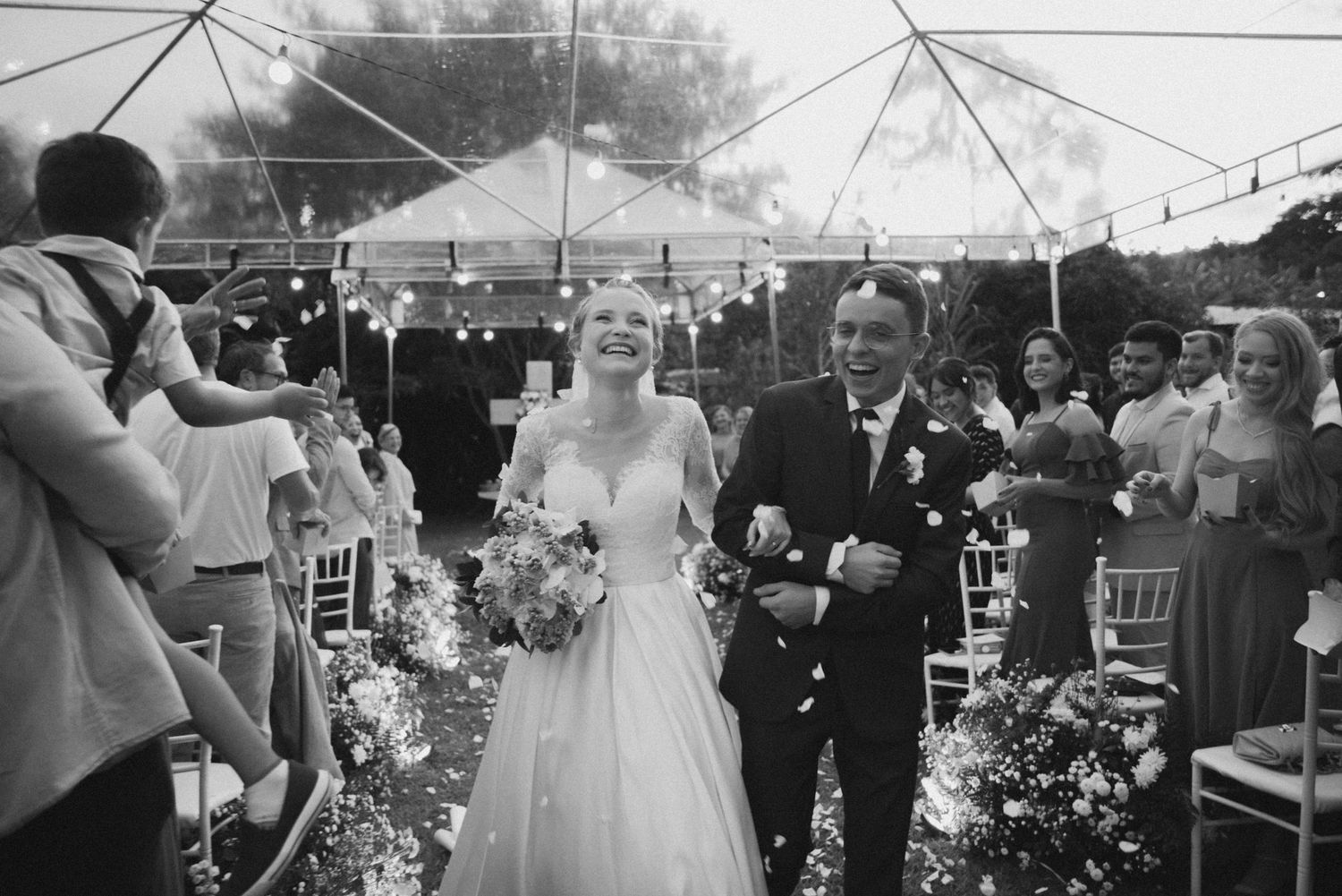 Wedding ceremony exit under a tent with flower petals lining the aisle.