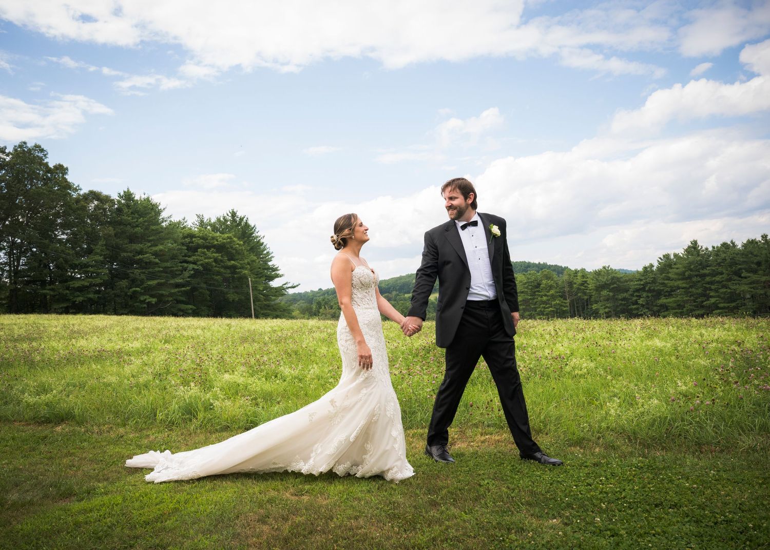 Newlyweds share an intimate moment outdoors with autumn foliage and rustic architecture in background.
