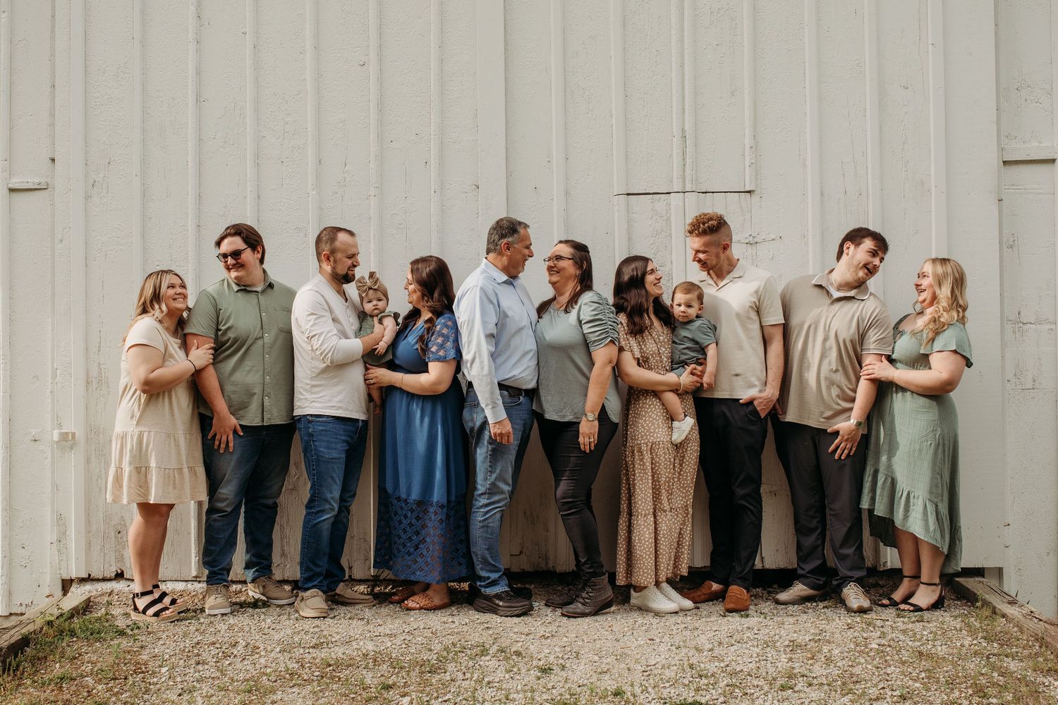 Family portrait series shows group posed casually against rustic barn wall.