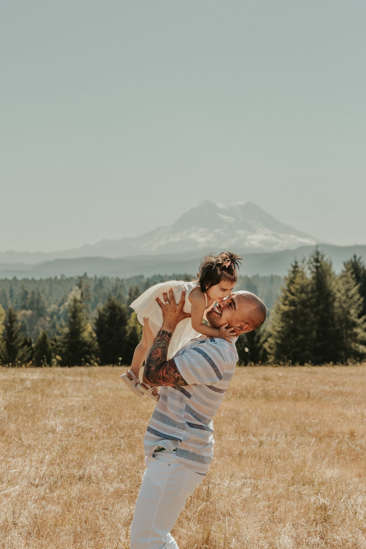 Kid-and-dad-laughing-and-playing-during-a-Spokane-family-photo-shoot-mountain-open-field-location