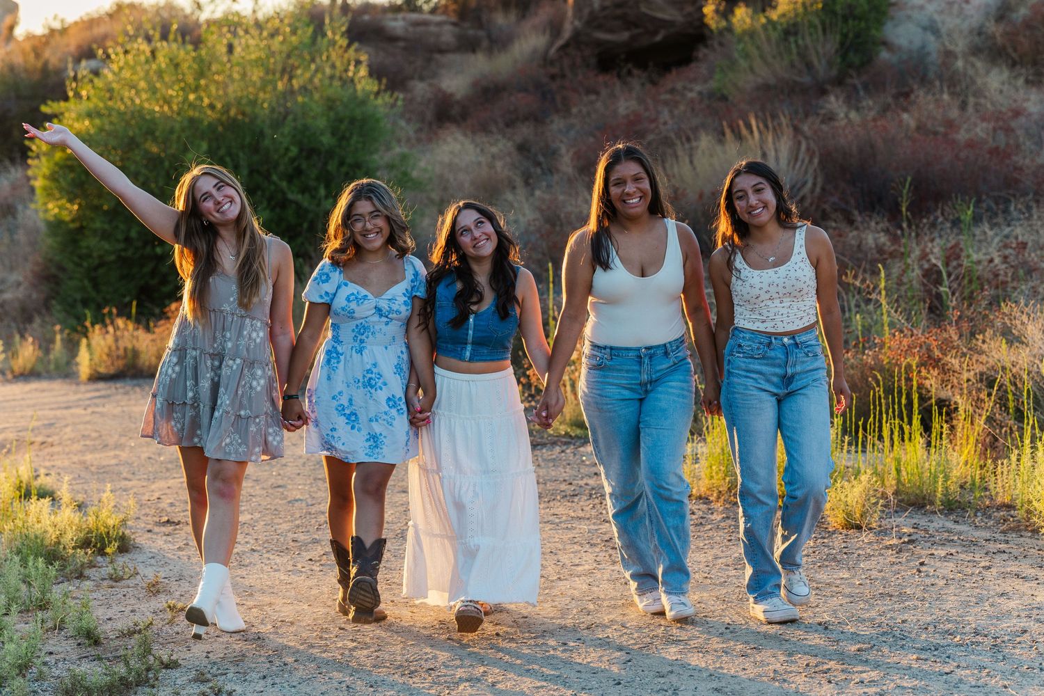 A group of five friends walking together on a dirt path at sunset in a desert landscape in. 2025 Simi Valley Senior Rep Team