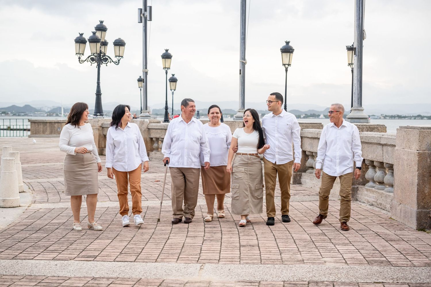 A group poses together on a cobblestone waterfront with vintage-style lampposts.