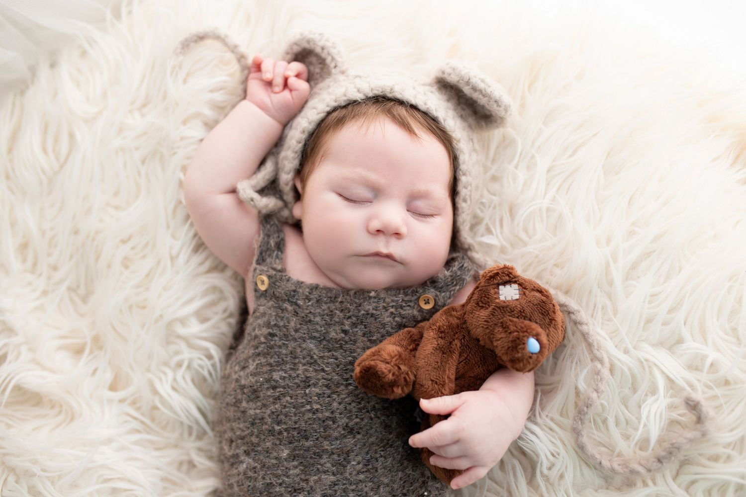 Newborn baby wearing bear bonnet and cuddling teddy bear, by little wonderland photography widnes cheshire newborn photoshoot