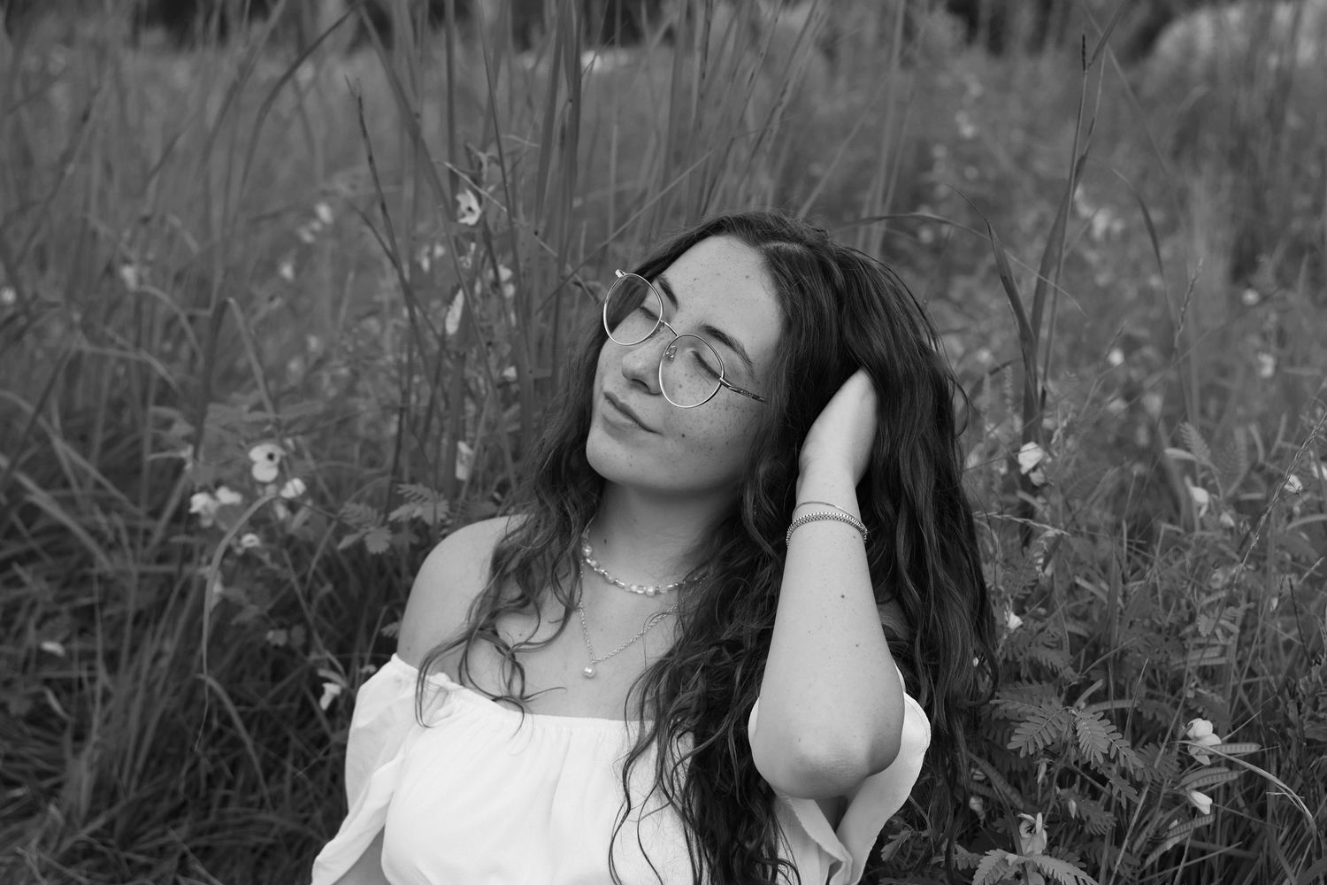 Artistic black and white portrait in tall grass with soft natural light.