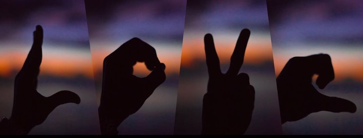 Silhouettes of hands against a purple sunset sky create an abstract pattern.