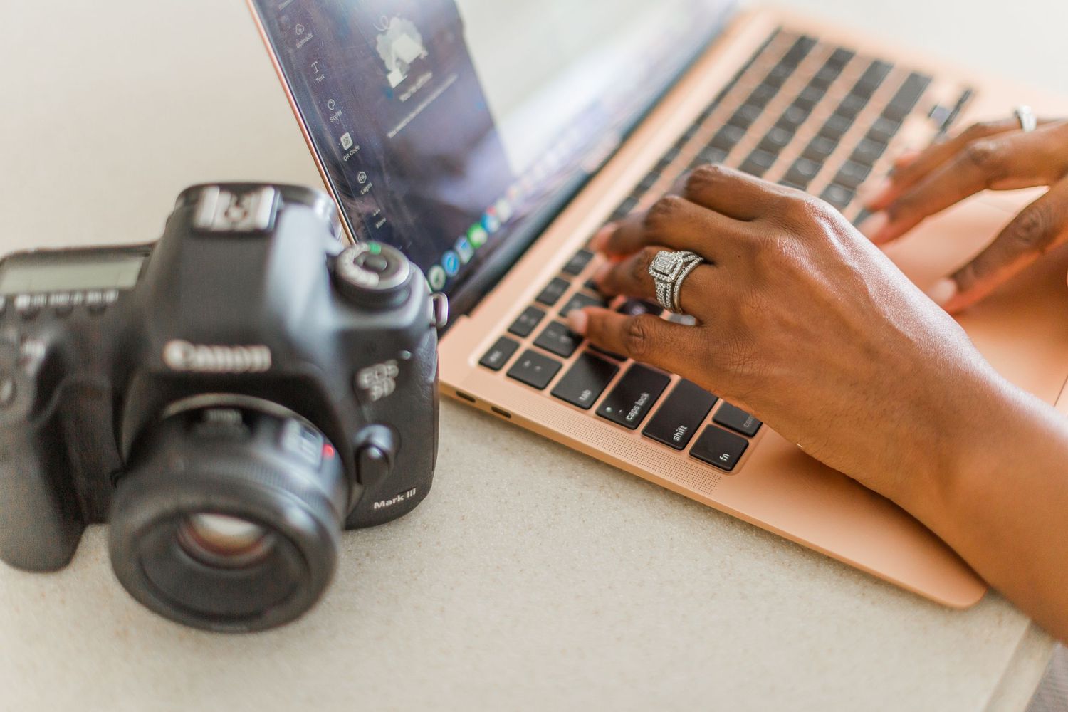 DSLR camera and laptop keyboard on desk during photo editing session.