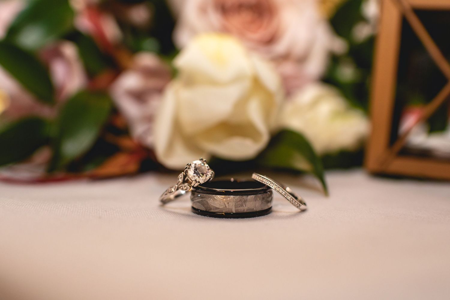 Wedding rings arranged artistically with roses and floral decor in the background.