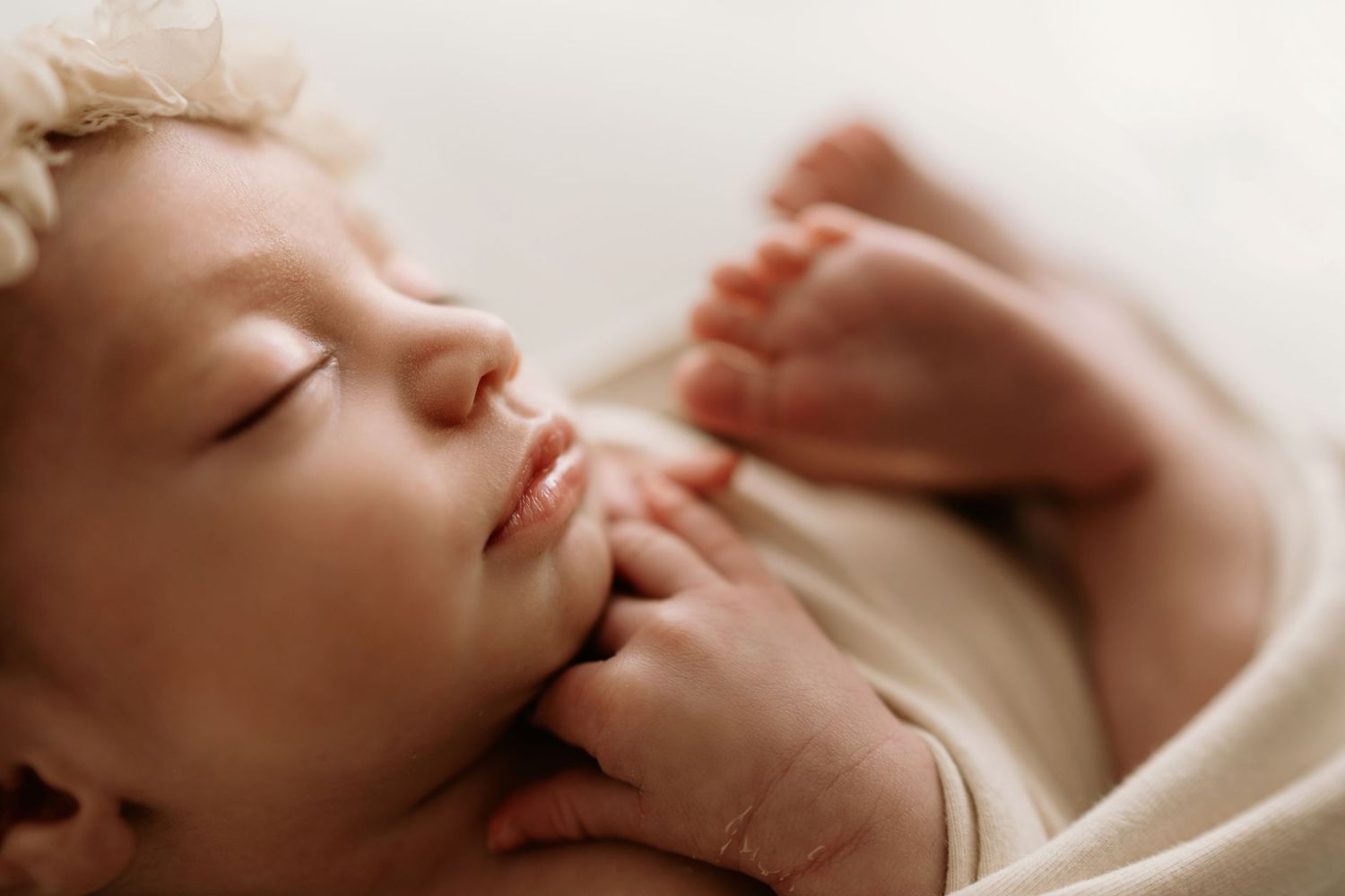 Peaceful sleeping newborn with soft natural lighting and gentle focus on facial features.