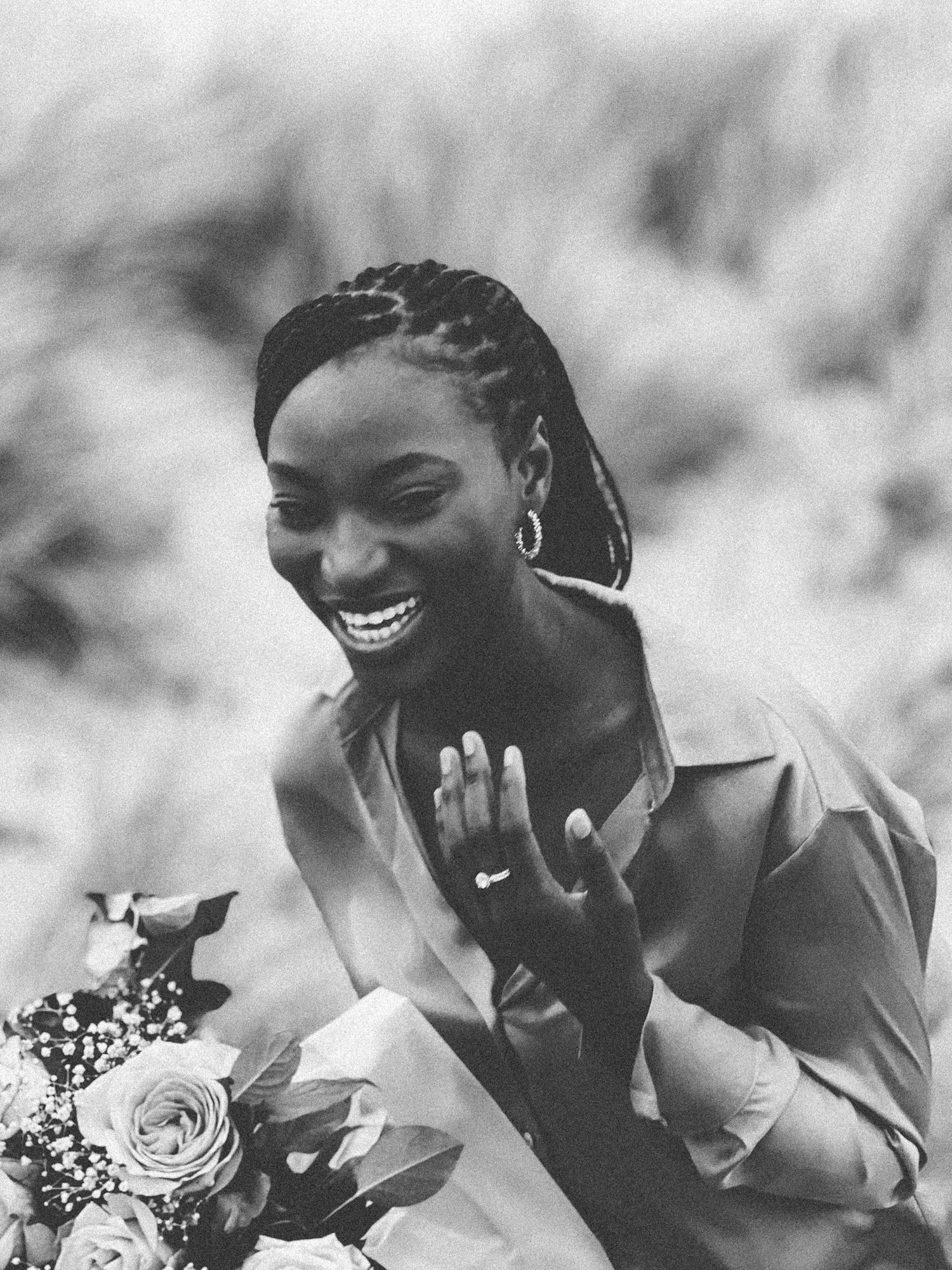 Black and white portrait of a radiant bride smiling while holding a floral bouquet.