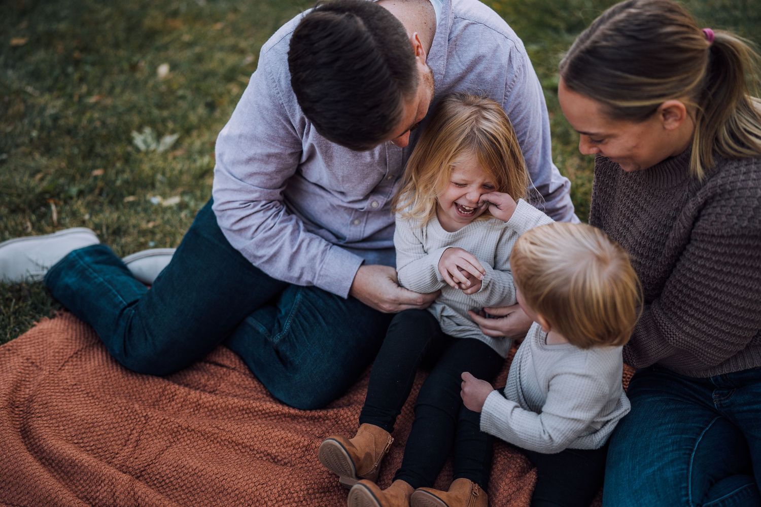 Playful outdoor family photography session with natural expressions and casual clothing.