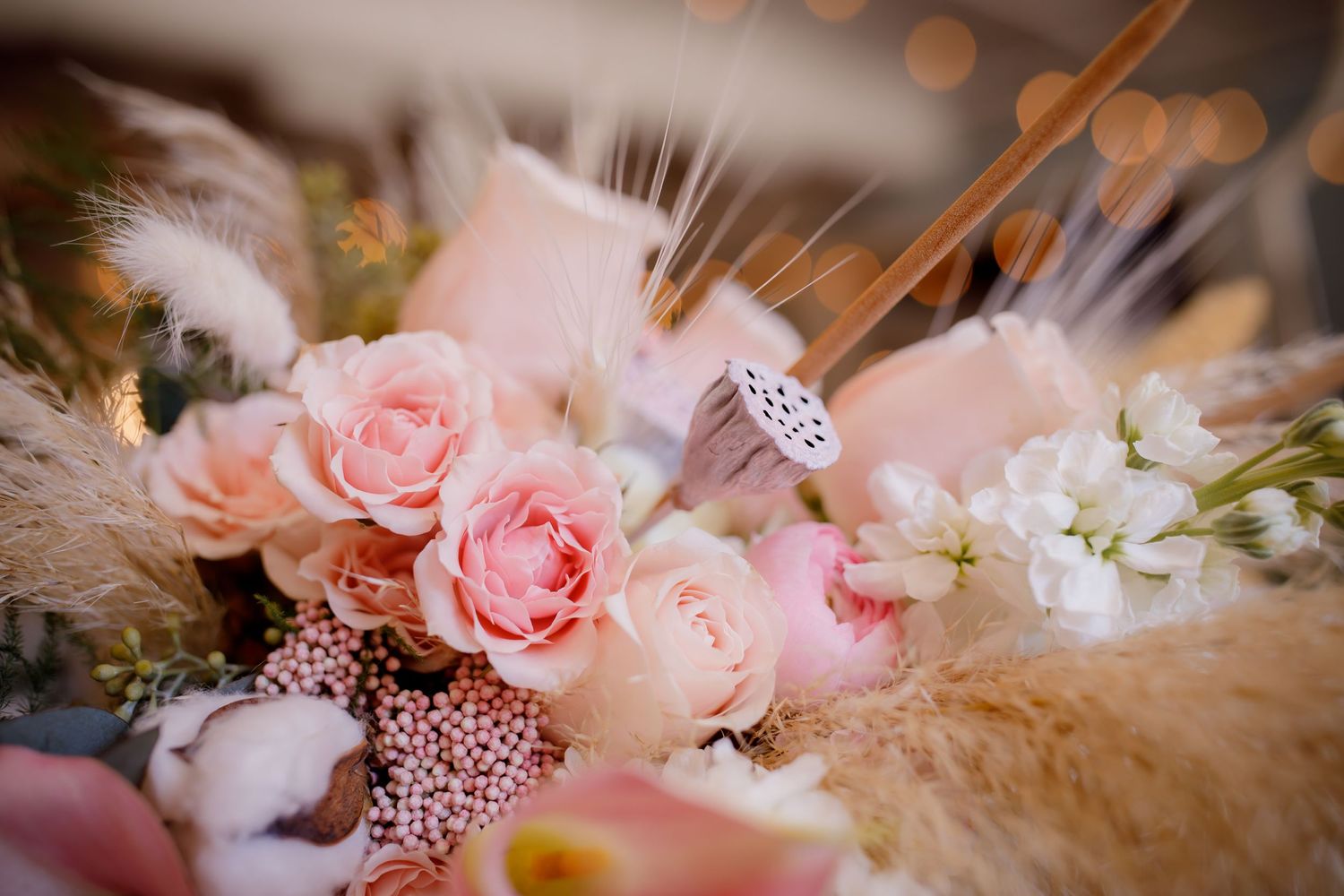 Close-up of a romantic pink wedding bouquet with roses, pampas grass, and a sparkling ring.