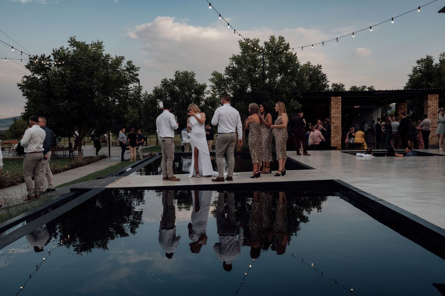 Bridal party standing by water with reflection of party in water, captured by Wouter Kleynhans at Pretoria venue