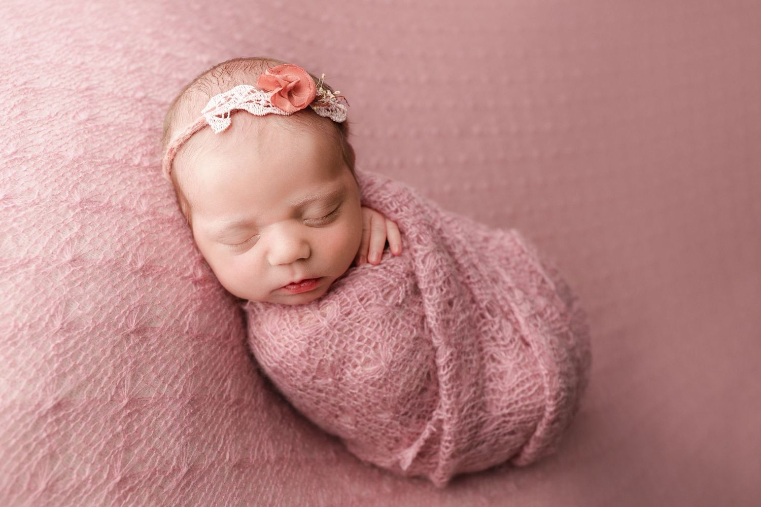 Fine art newborn portrait of baby girl wrapped in pink