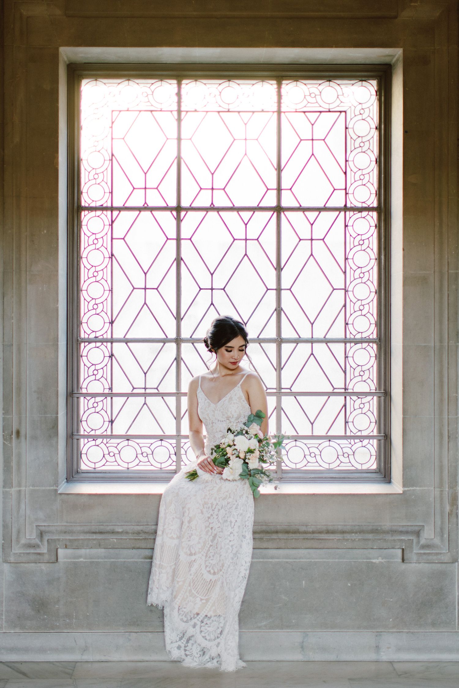 Elegant bridal portrait against ornate geometric window.
